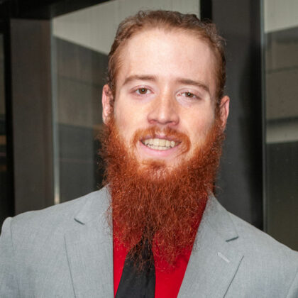 UofL-Student Daniel Hodges. Er trägt ein Hemd mit roten Knöpfen und einen grauen Blazer mit einer schwarzen Krawatte.