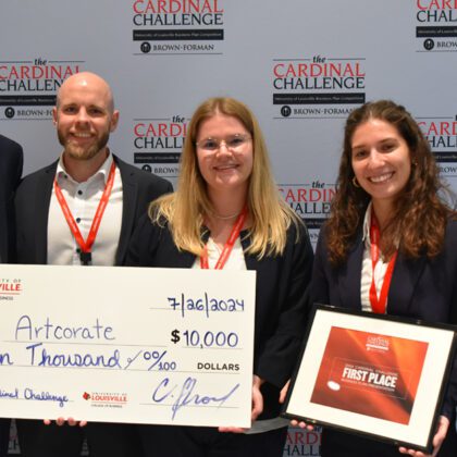 Team members of Artcorate, winners of the 2024 Cardinal Challenge competition, pose in front of a background with the Cardinal Challenge logo. They are holding a framed certificate and a large check with $10,000 written on it.