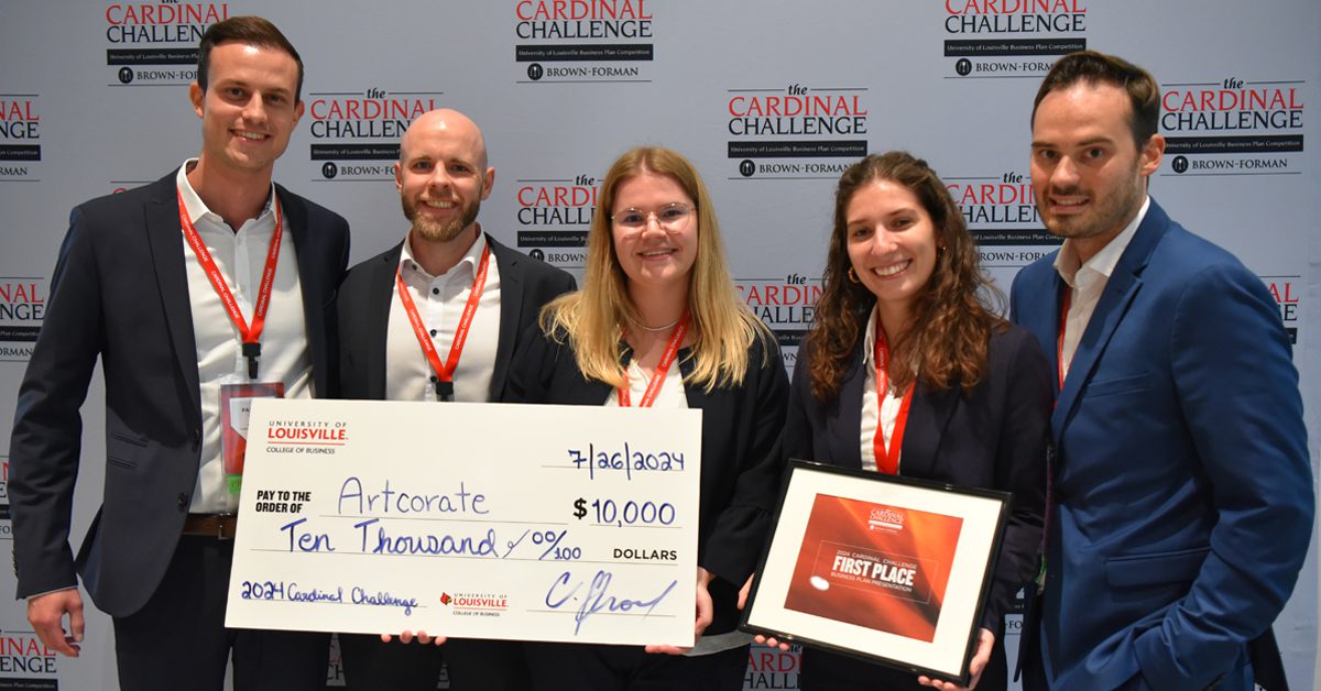 Team members of Artcorate, winners of the 2024 Cardinal Challenge competition, pose in front of a background with the Cardinal Challenge logo. They are holding a framed certificate and a large check with $10,000 written on it.