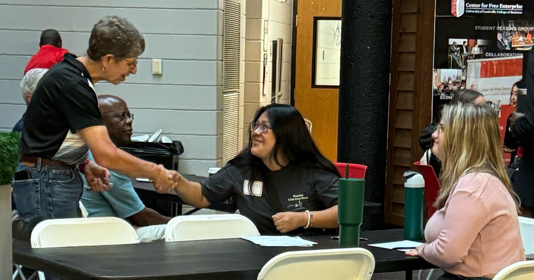 A faculty member speaks to new students at an open house event