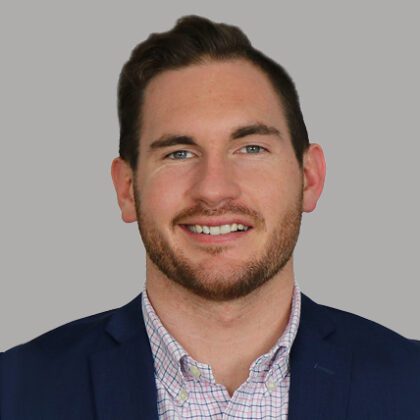 President of the Young Professionals of Louisville, Ben Donlon, poses for a professional headshot in front of a gray background.