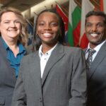 Sakthiraj Kandasamy, Susan Miracle and Hope Odubena stand in front of international flags in Frazier Hall on the UofL campus