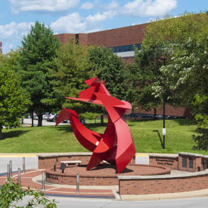 Middle distance shot of Big Red scuplture with trees in the foreground