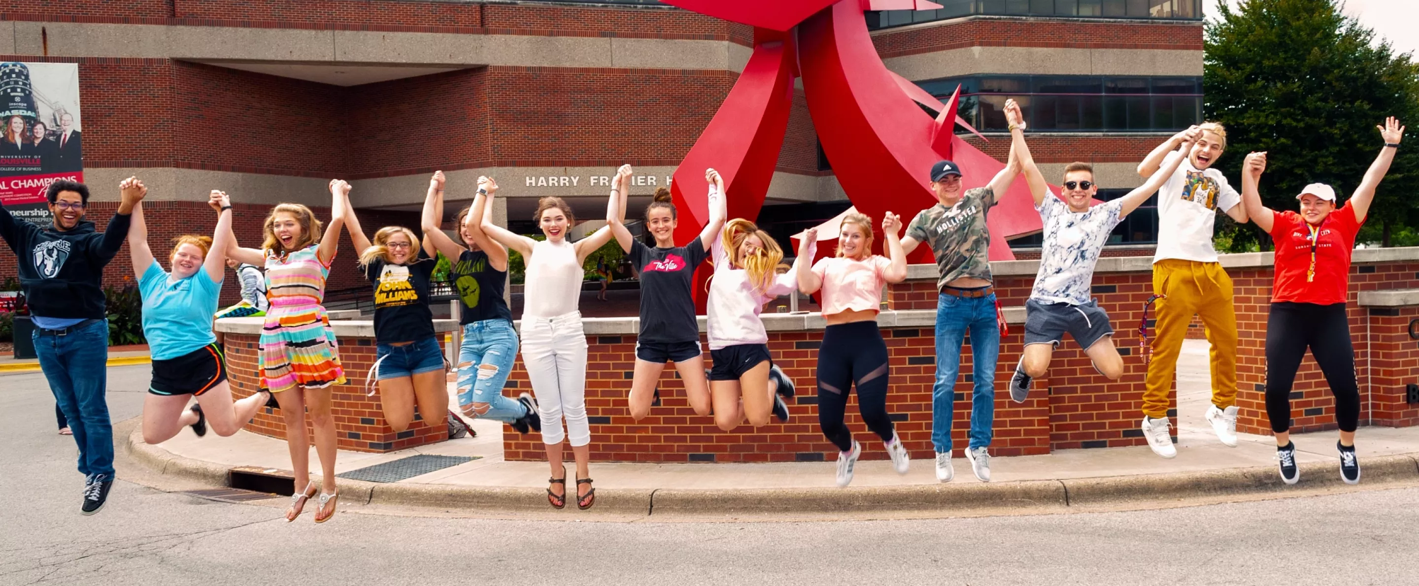 College of Business Students jumping in front of the Big Red Statue