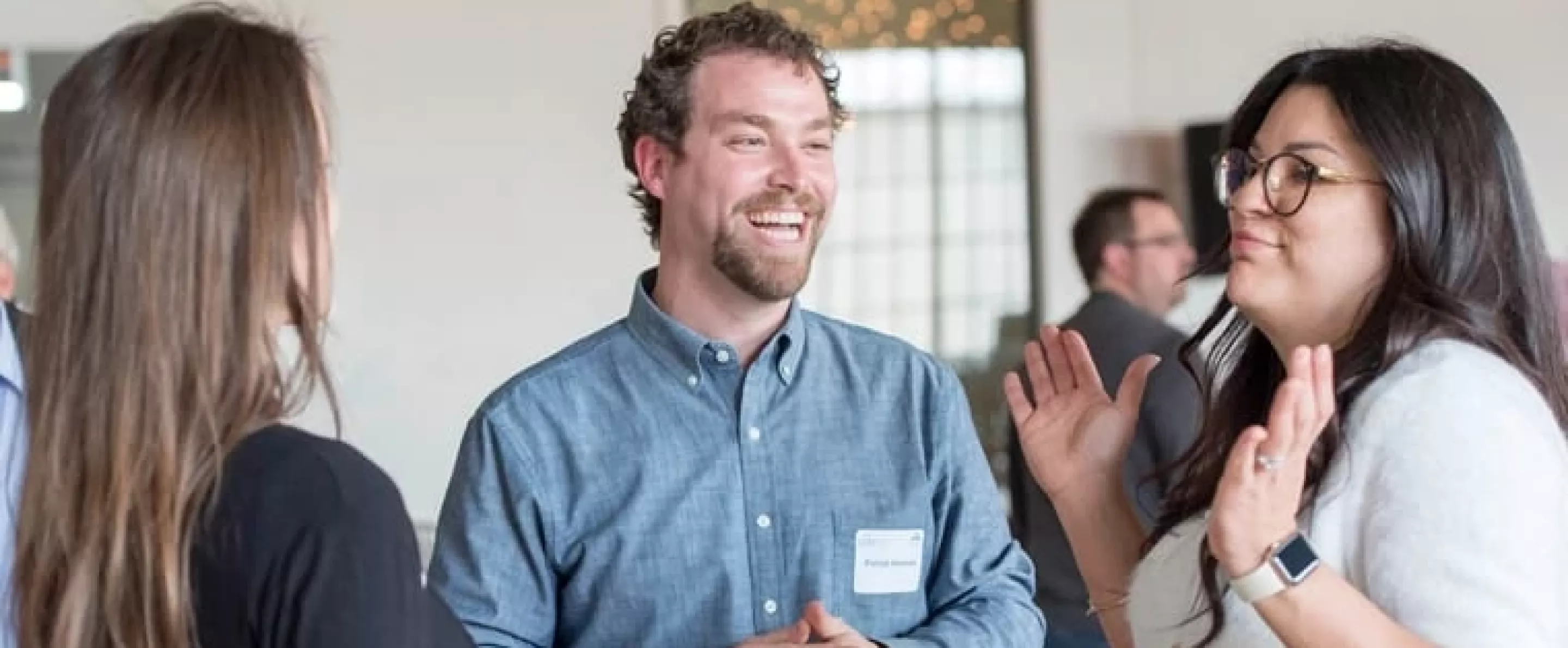 Group of three laughing and having a conversation at a UfoL College of Business Forcht Center event