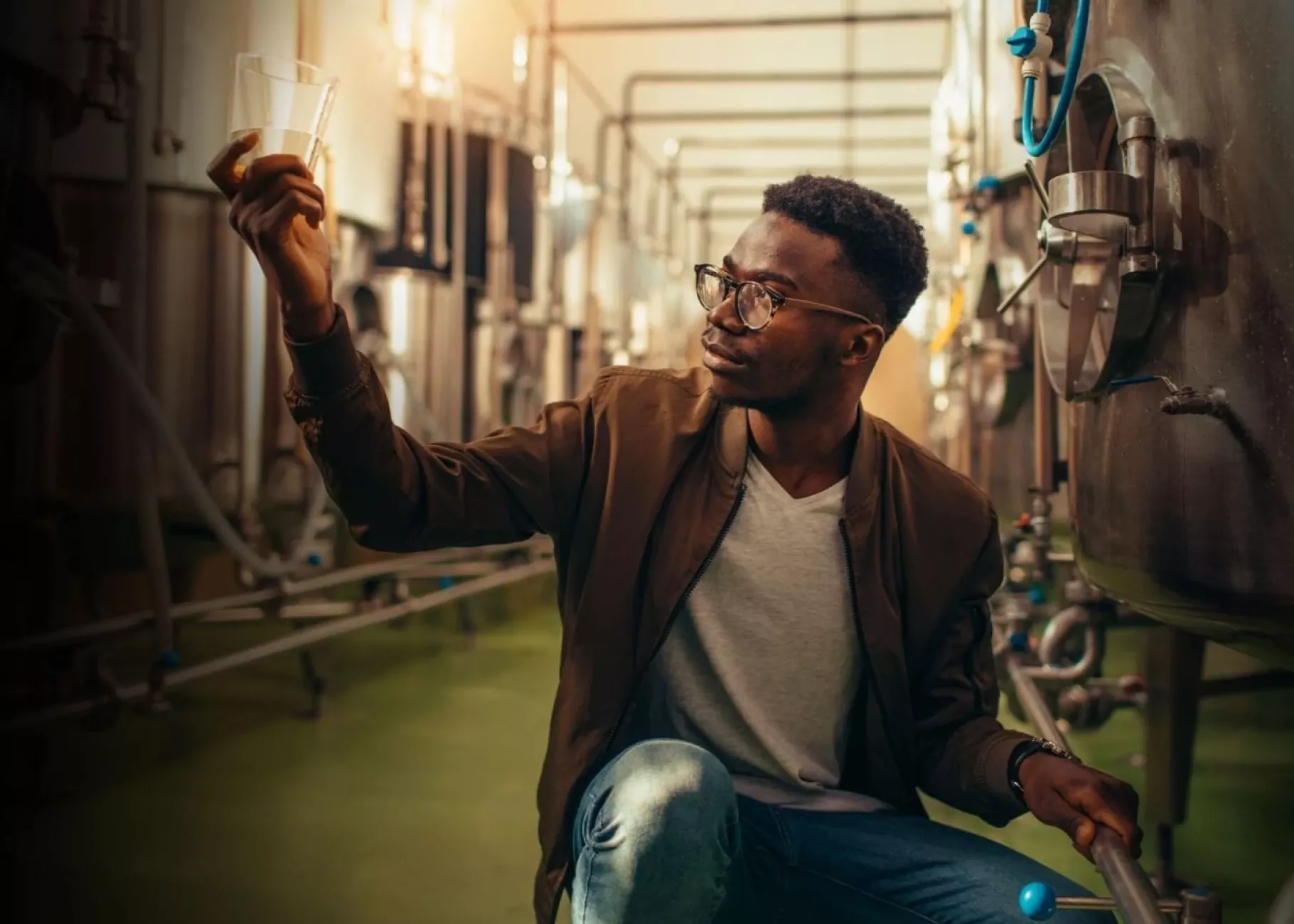 Man analyzes alcohol next to distillery equipment