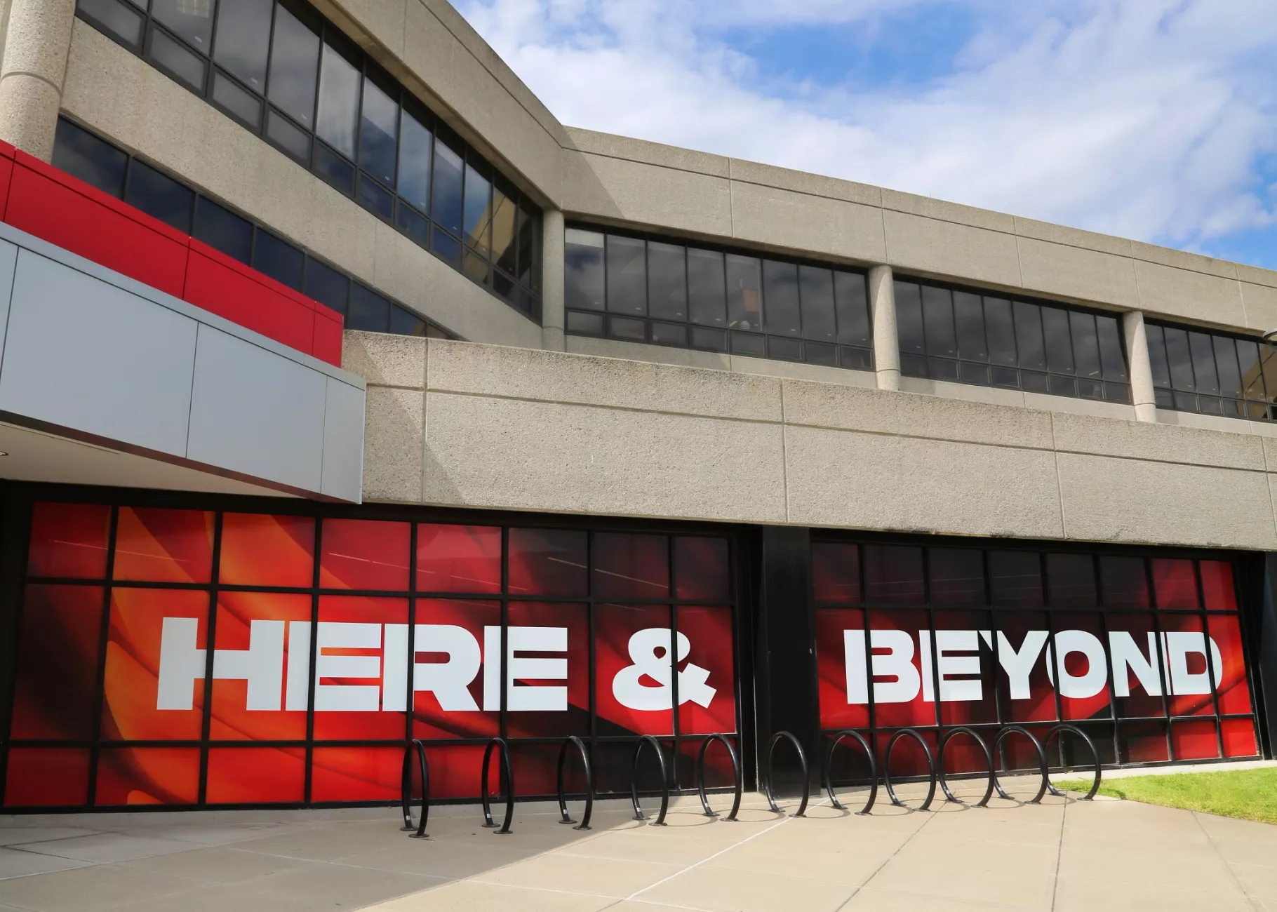 UofL windows in the student activity center covered in UofL Here and Beyond branding art. The windows are on the ground…