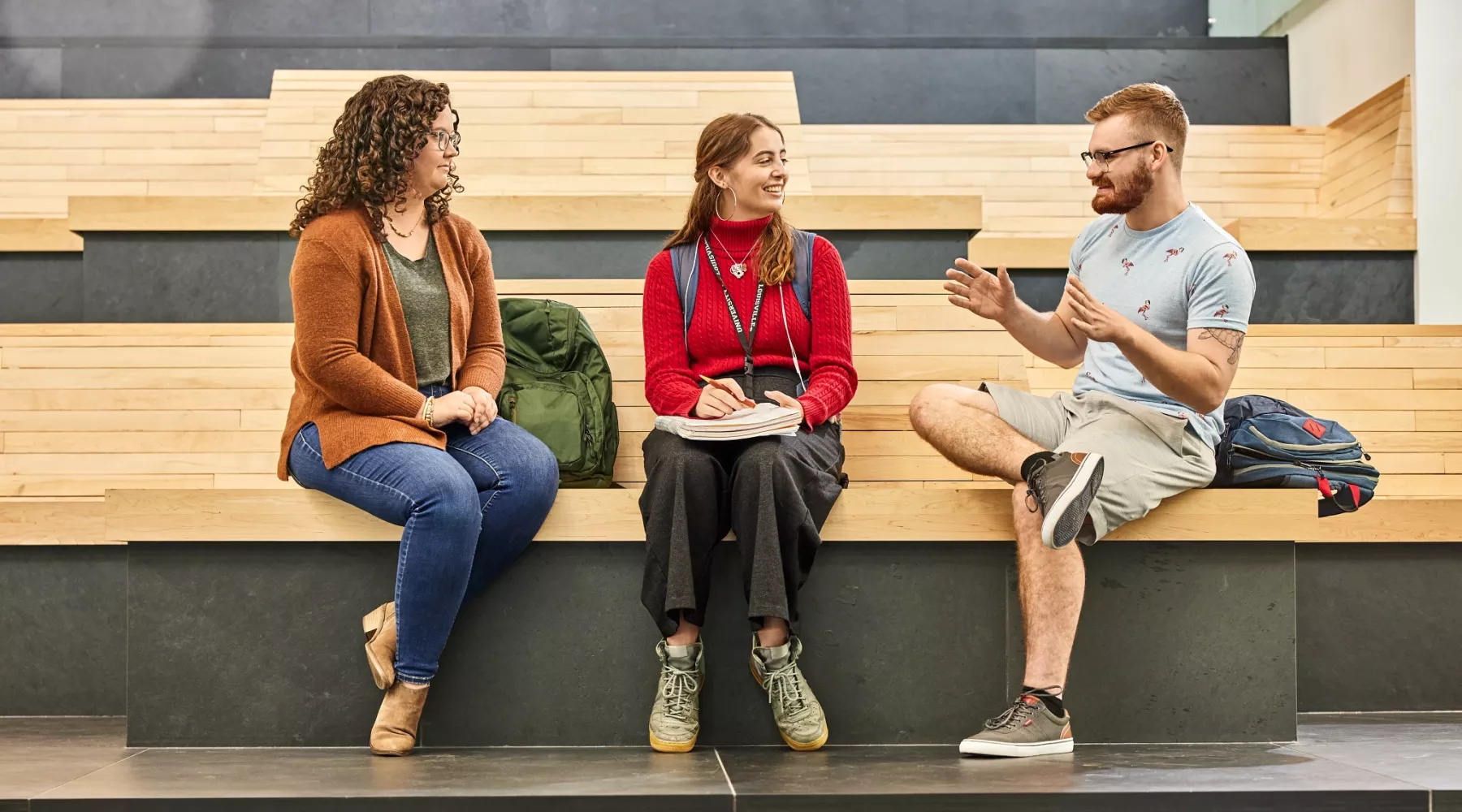 Alison Williams sitting on the wooden benches within the entrance of the Belknap Academic Building