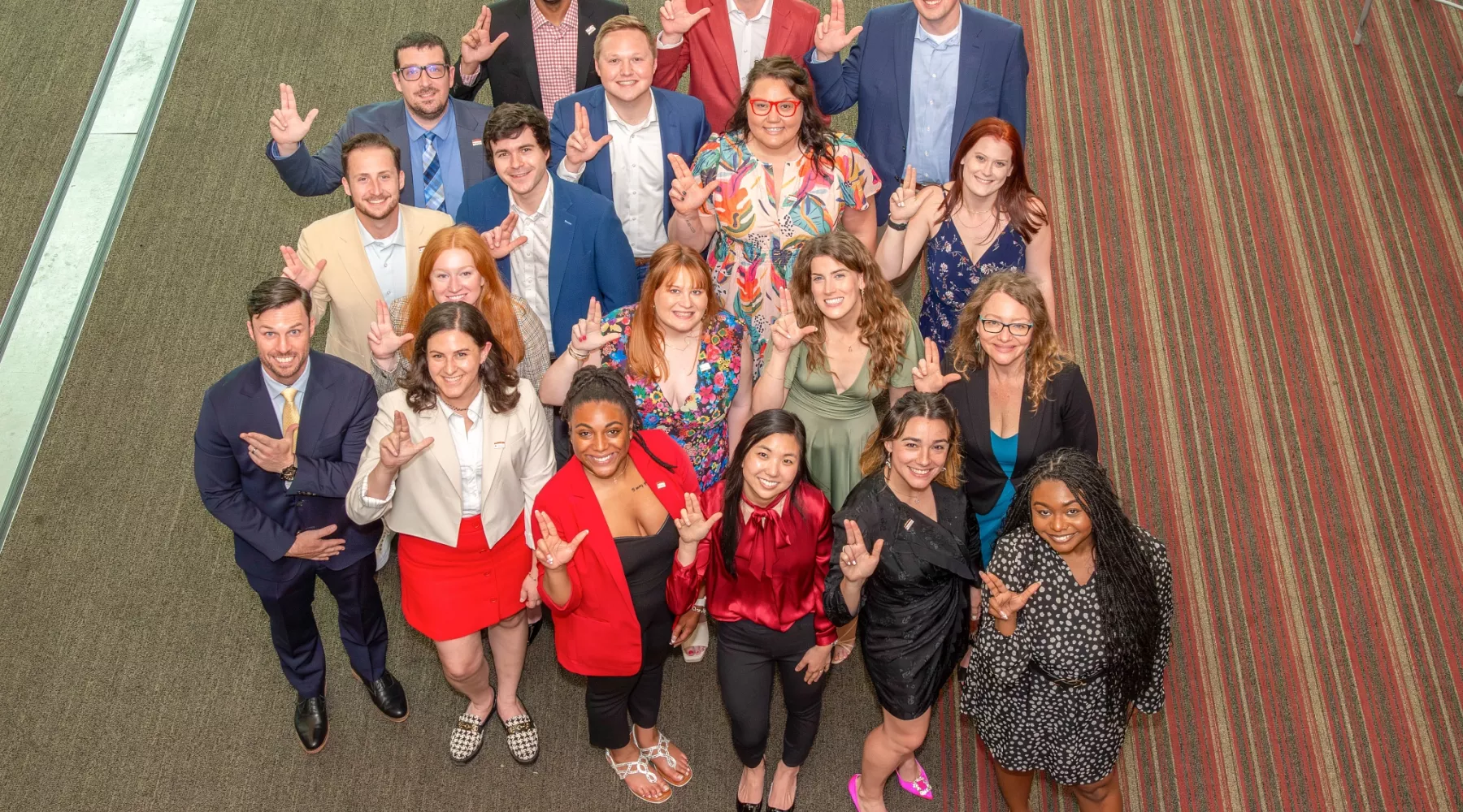 UofL CoB Professional MBA Fall22 cohort group pose looking up with their L's up at the final graduation celebration in the PNC Club