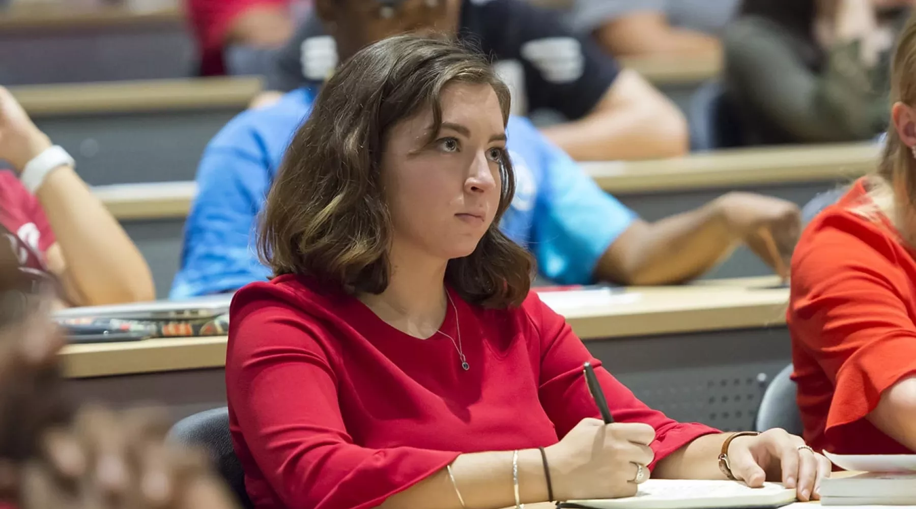 College of Business student writing notes during a class lecture in the PNC Horn auditorium.
