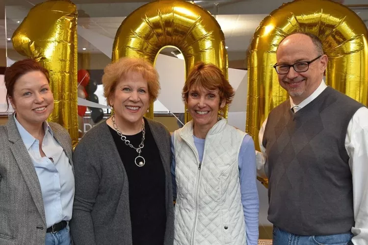 Four people standing in front of balloons.
