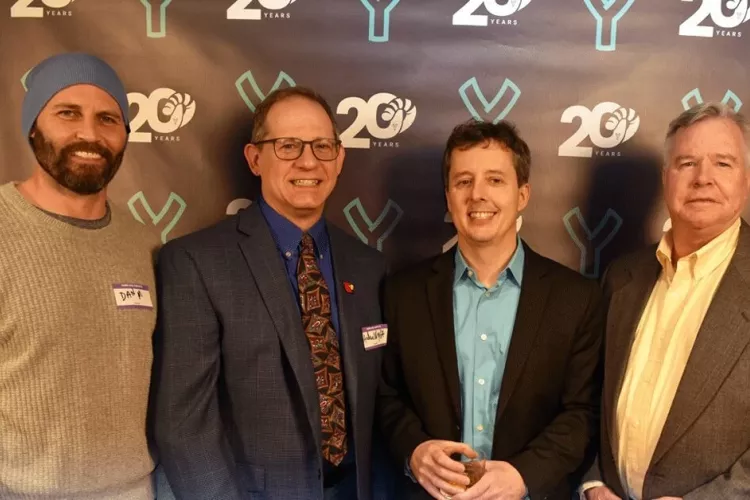 Four men posing in front of a banner.