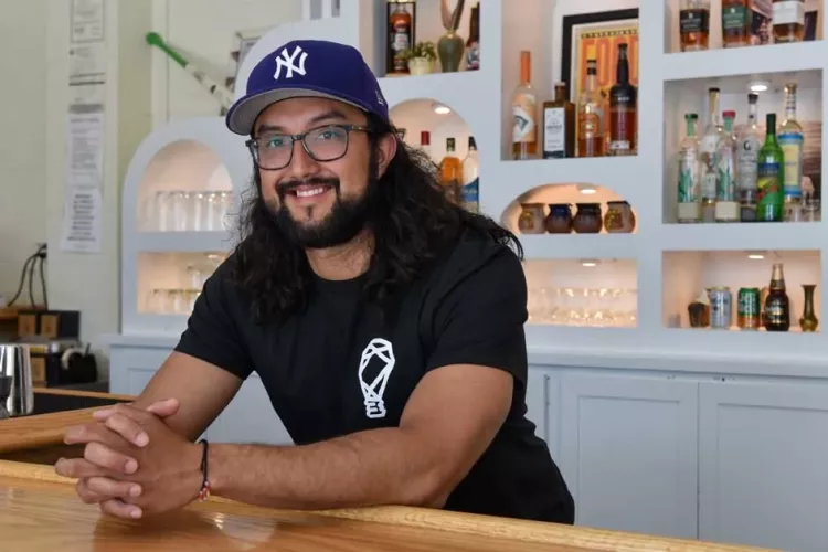Josh Gonzalez leaning over the bar at his restaurant, FOKO