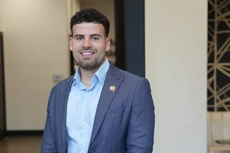 Alumni Nima Asgari in blue coat and shirt posing for photo.