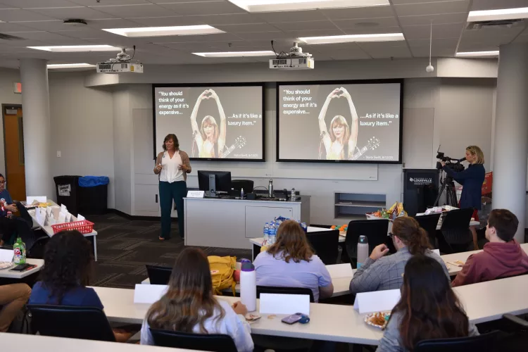 Beth Munnich speaking to a group in front of a presentation with Taylor Swift pictured.