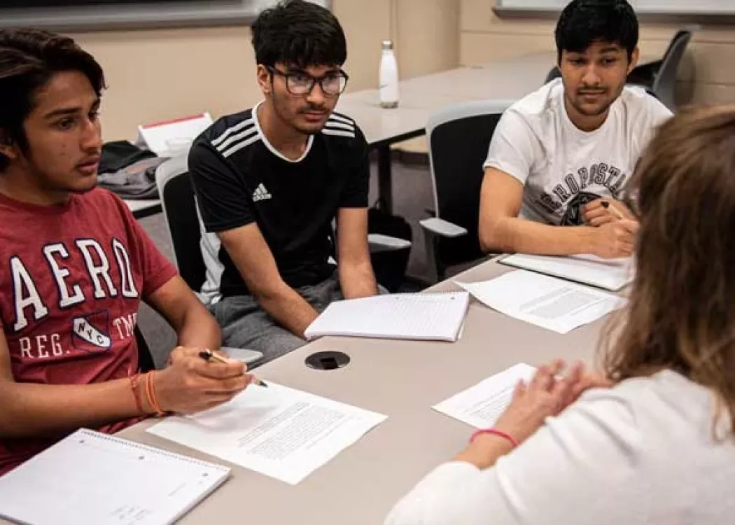 A group of students working alongside their teacher in a College of Business classroom.