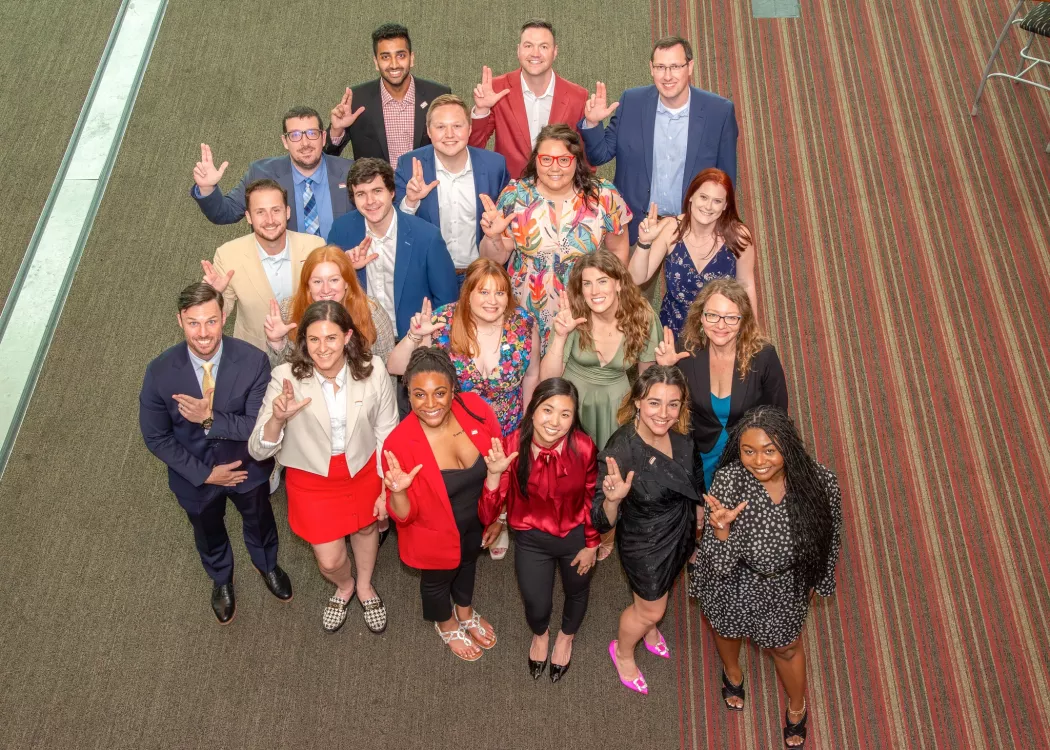 UofL CoB Professional MBA Fall22 cohort group pose looking up with their L's up at the final graduation celebration in the PNC Club