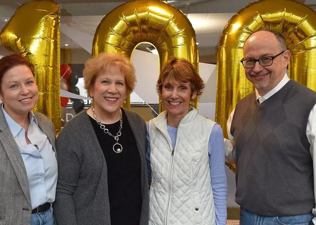 Four people standing in front of balloons.