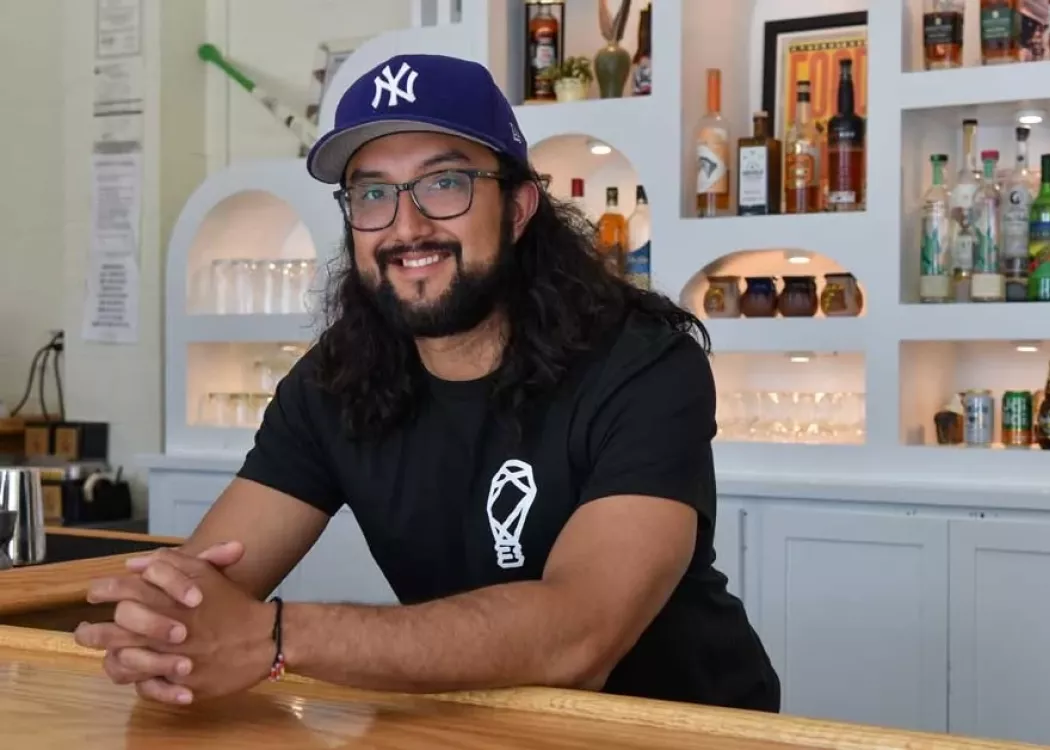 Josh Gonzalez leaning over the bar at his restaurant, FOKO