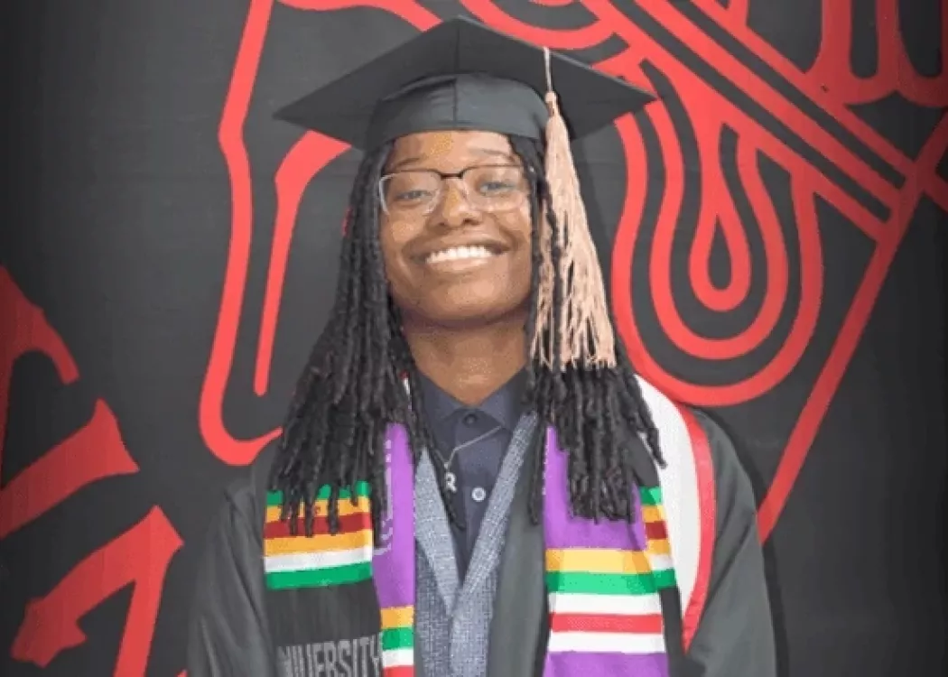 Taylor Price in commencement regalia posing for photo