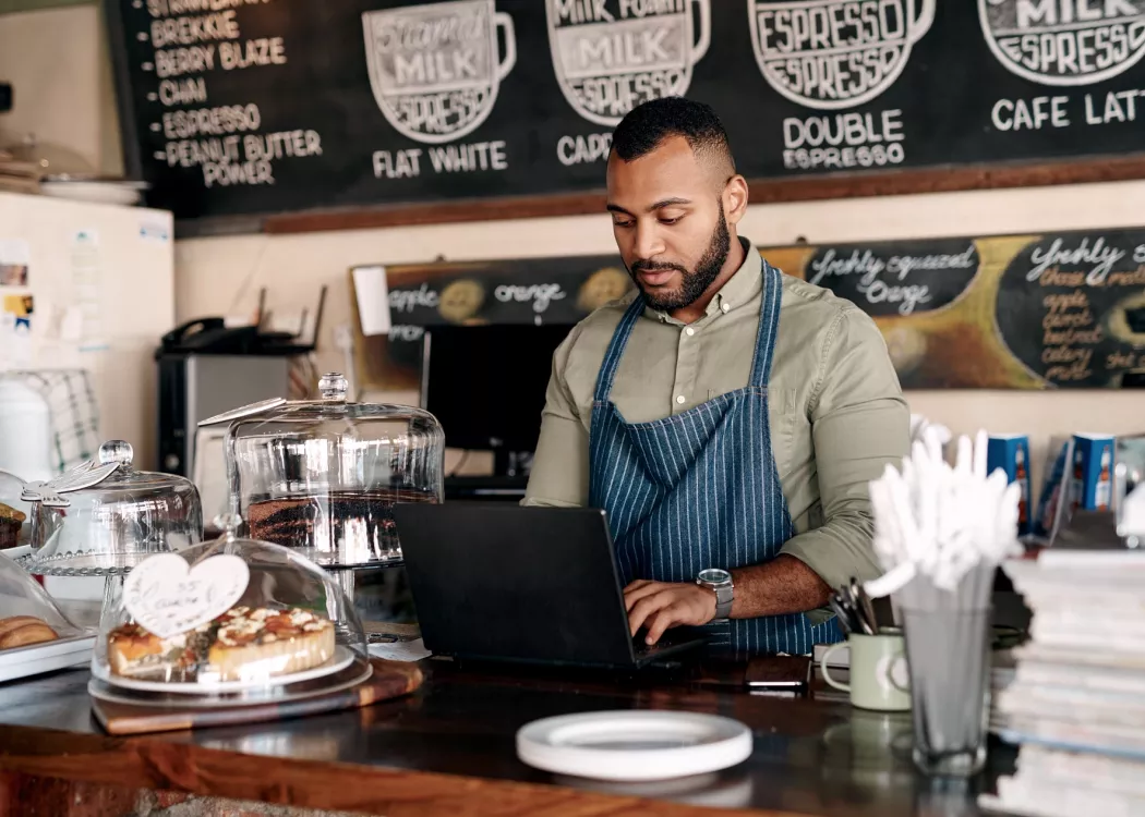 A young man using a laptop while working in a cafe