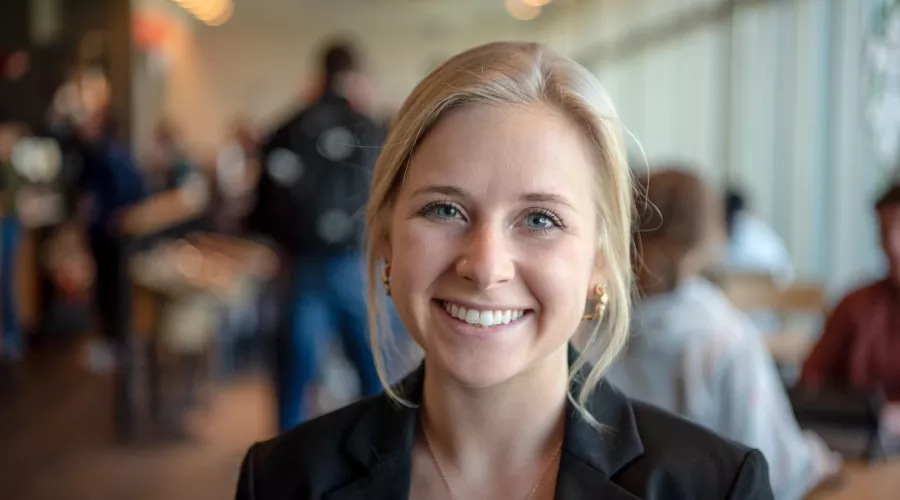 Student portrait smiling in a busy cafe on campus