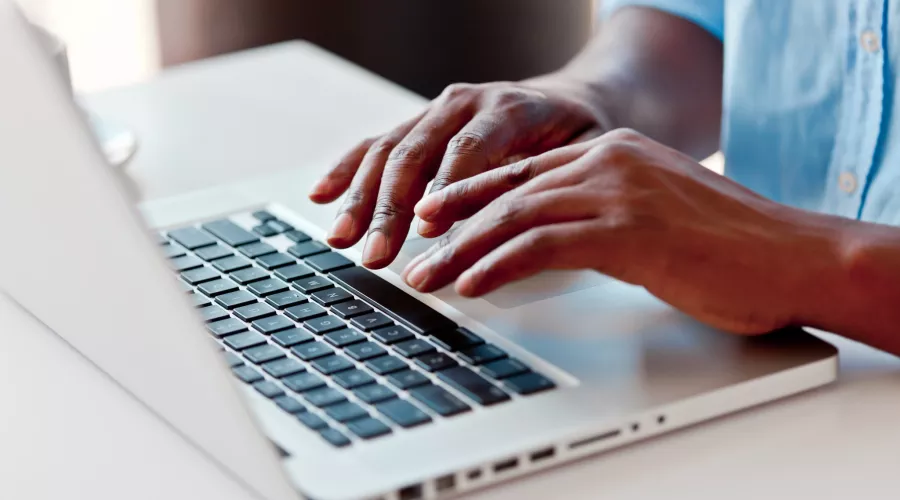 Close-up on male hands typing on laptop keyboard.