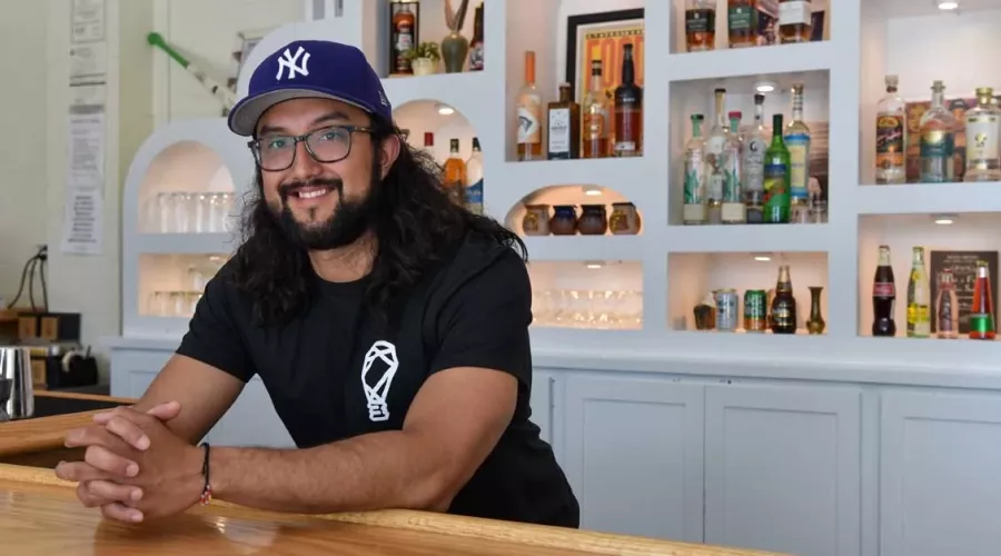 Josh Gonzalez leaning over the bar at his restaurant, FOKO