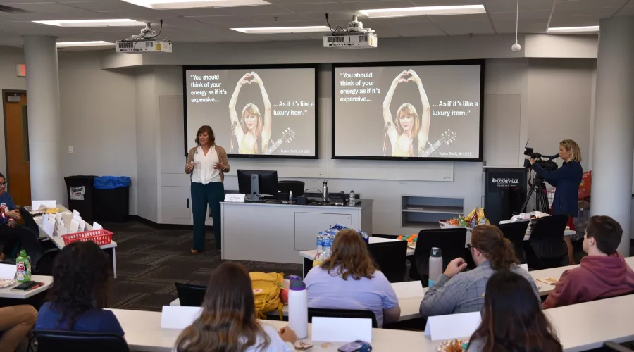 Beth Munnich speaking to a group in front of a presentation with Taylor Swift pictured.