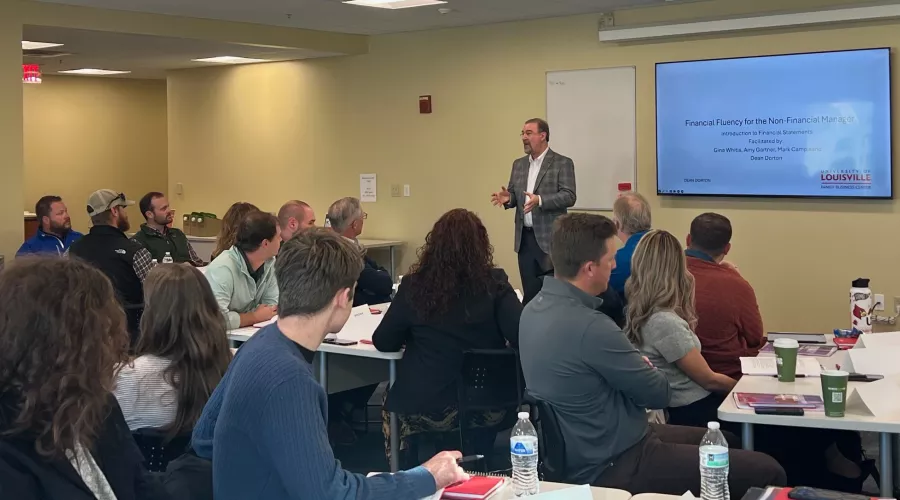 Man at the front of a classroom speaking.