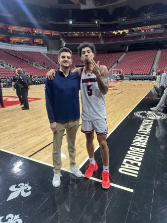 Ethan Coury stands with client and UofL Men’s Basketball team member Terrence Edwards, Jr. on the sidelines of the KFC…