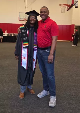 Taylor Price in commencement regalia posing for photo with Raymond Green